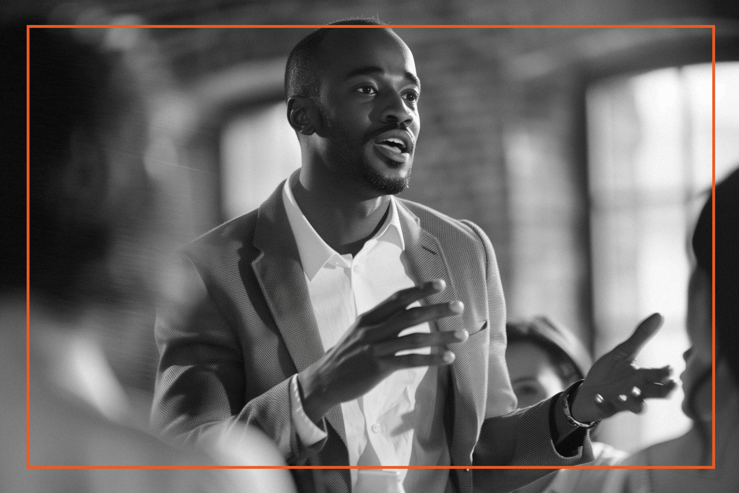 A professional man in a business suit is passionately speaking to an audience, illustrating leadership and cultural change in a modern workplace setting.